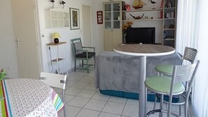 Un espacio habitable compacto con comedor, televisor y estantería.