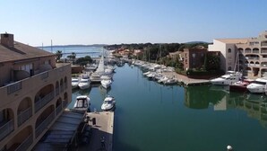 Un puerto deportivo con barcos amarrados, un puente al fondo y edificios con balcones.