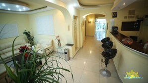 A modern hotel lobby with a sofa, a coffee machine, and a reception desk. - Vila Diandra (Eforie)