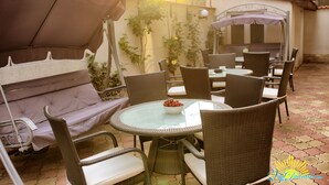 An outdoor patio with wicker furniture, a glass table with a bowl of fruit, and a covered seating area. - Vila Diandra (Eforie)