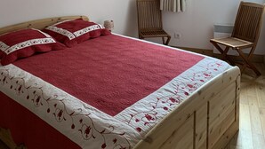 A bedroom with a wooden bed, a window with curtains, a chair, and a radiator. - B205 - 58 m2 - 3P - 6 pers (Prapoutel)