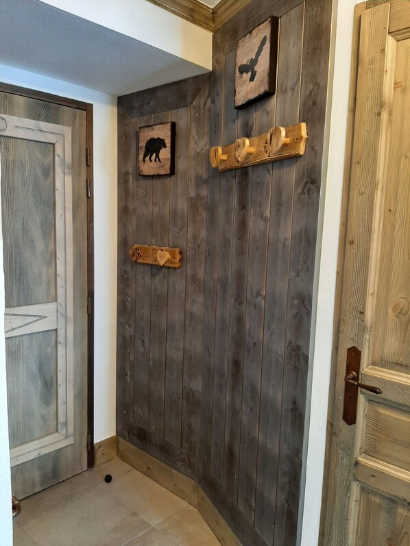 A wooden door with a rustic design, a small animal picture, and a wooden shelf with a decorative item.