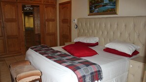 Un dormitorio con cama, una banca y armarios de madera.