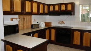 Una cocina con armarios de madera, microondas, tostadora y cafetera.