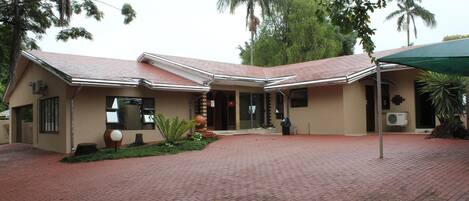 A building with a red-tiled roof, a brick-paved entrance, and a covered area with a green canopy.