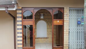Fachada de edificio de ladrillo, con puertas dobles de madera y una reja metálica.