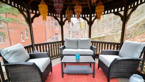A covered patio with wicker furniture, a red patterned rug, and hanging lanterns. - Däs Barenhaus on Broadway (4 Master Bedrooms) (Jim Thorpe)