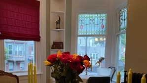 A dining area with a table, chairs, a vase with flowers, and candle holders. - Däs Barenhaus on Broadway (4 Master Bedrooms) (Jim Thorpe)