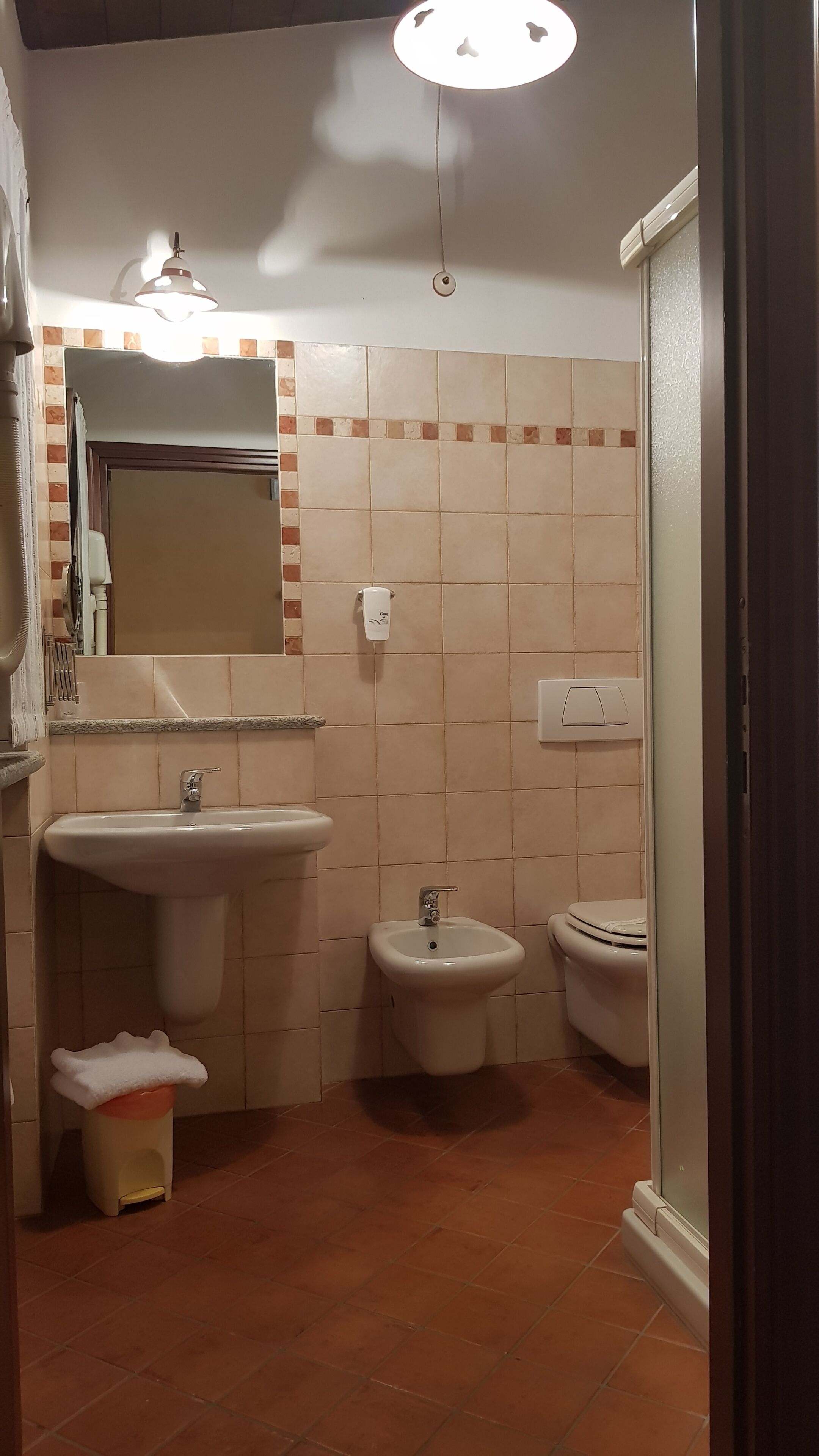 Een badkamer met een wastafel, bidet en toilet, betegelde wanden en een spiegel.