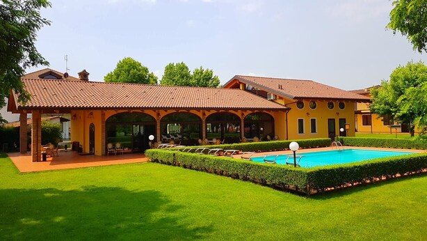 Un bâtiment à deux étages doté d’une piscine, d’un patio couvert et d’une pelouse bien entretenue.