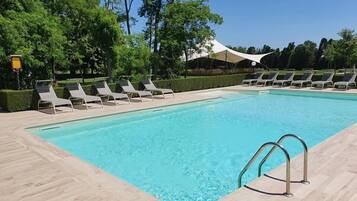 A swimming pool with lounge chairs and a covered area.