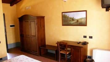 Une pièce comprenant un lit, un bureau en bois, une chaise et un tableau accroché au mur.