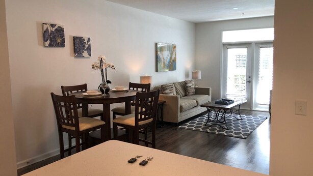 Un espace repas comprenant une table et des chaises, un canapé, une lampe et des œuvres d’art accrochées aux murs.