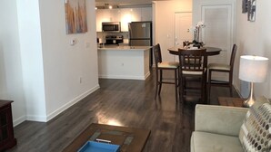 Un salon moderne comprenant un canapé, une table à manger avec des chaises et un coin cuisine équipé d’appareils électroménagers.