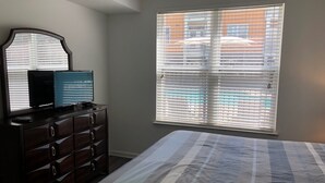 Une chambre à coucher avec un lit, une commode et une fenêtre équipée de stores.