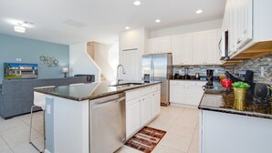 A modern kitchen with white cabinets, stainless steel appliances, and a granite countertop.