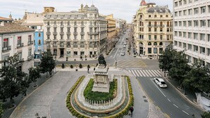 Una plaza urbana con una fuente central, rodeada de edificios históricos de arquitectura clásica.
