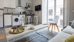 A modern kitchen with a washing machine, microwave, and a dining area with a table and chairs. - Genteel Home Trinidad Grund F (Málaga)