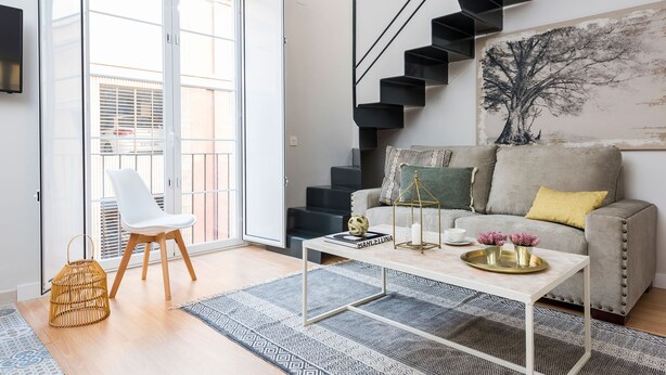 A modern living room with a sofa, coffee table, and a staircase. - Genteel Home Trinidad Grund F (Málaga)
