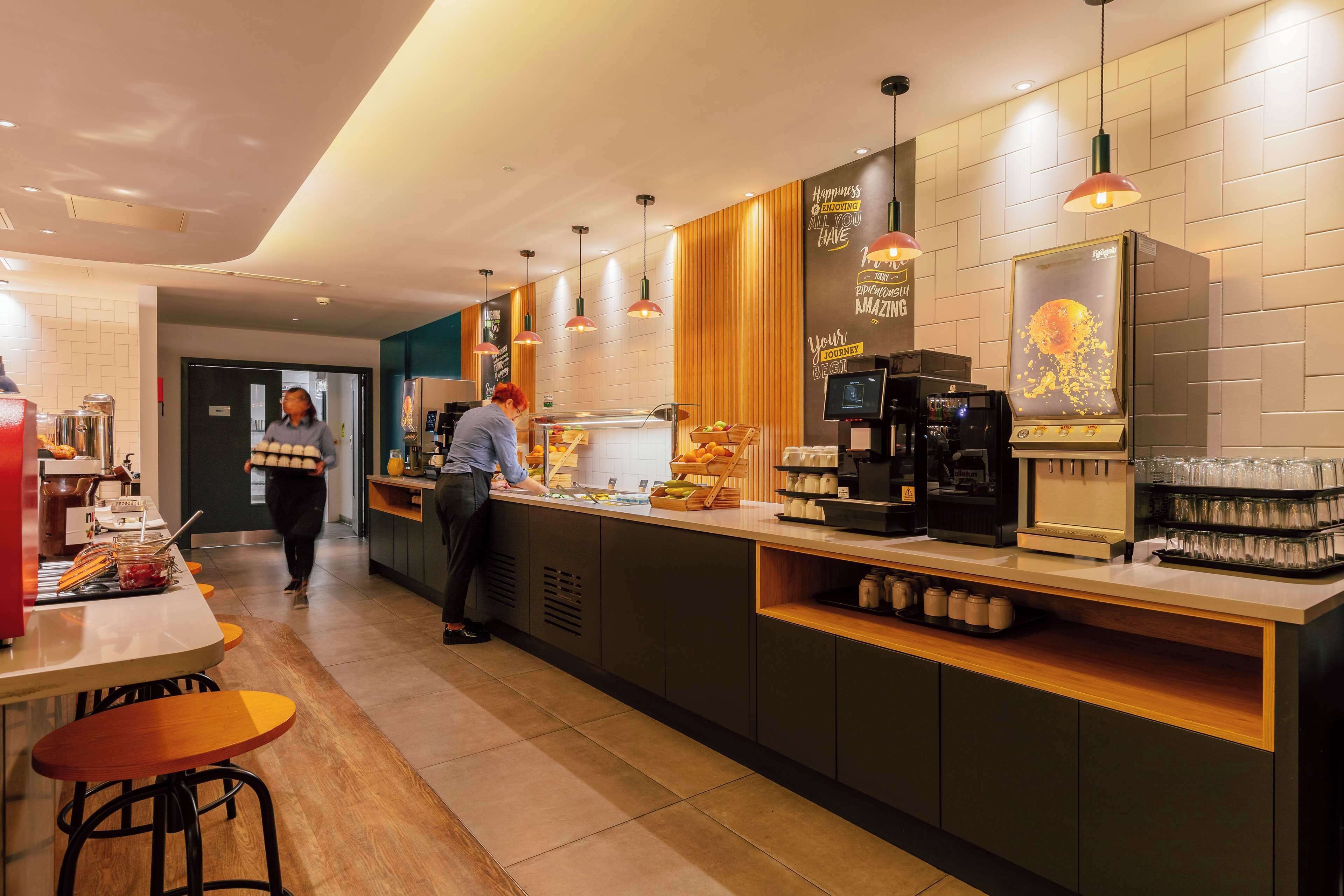 A modern cafe with a counter, bar stools, and a coffee machine.