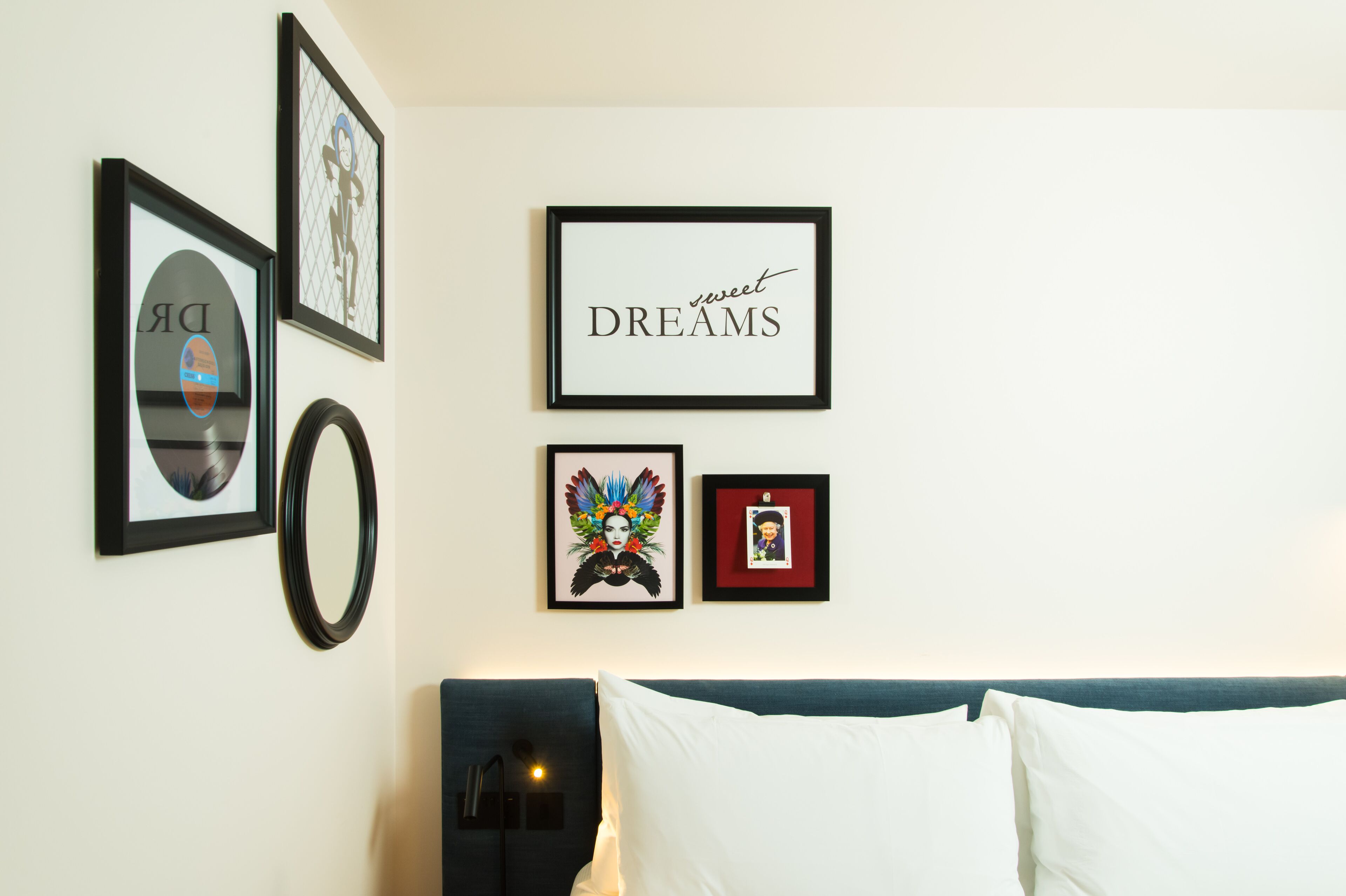 Una camera da letto con un letto, una lampada a parete e diverse foto incorniciate.