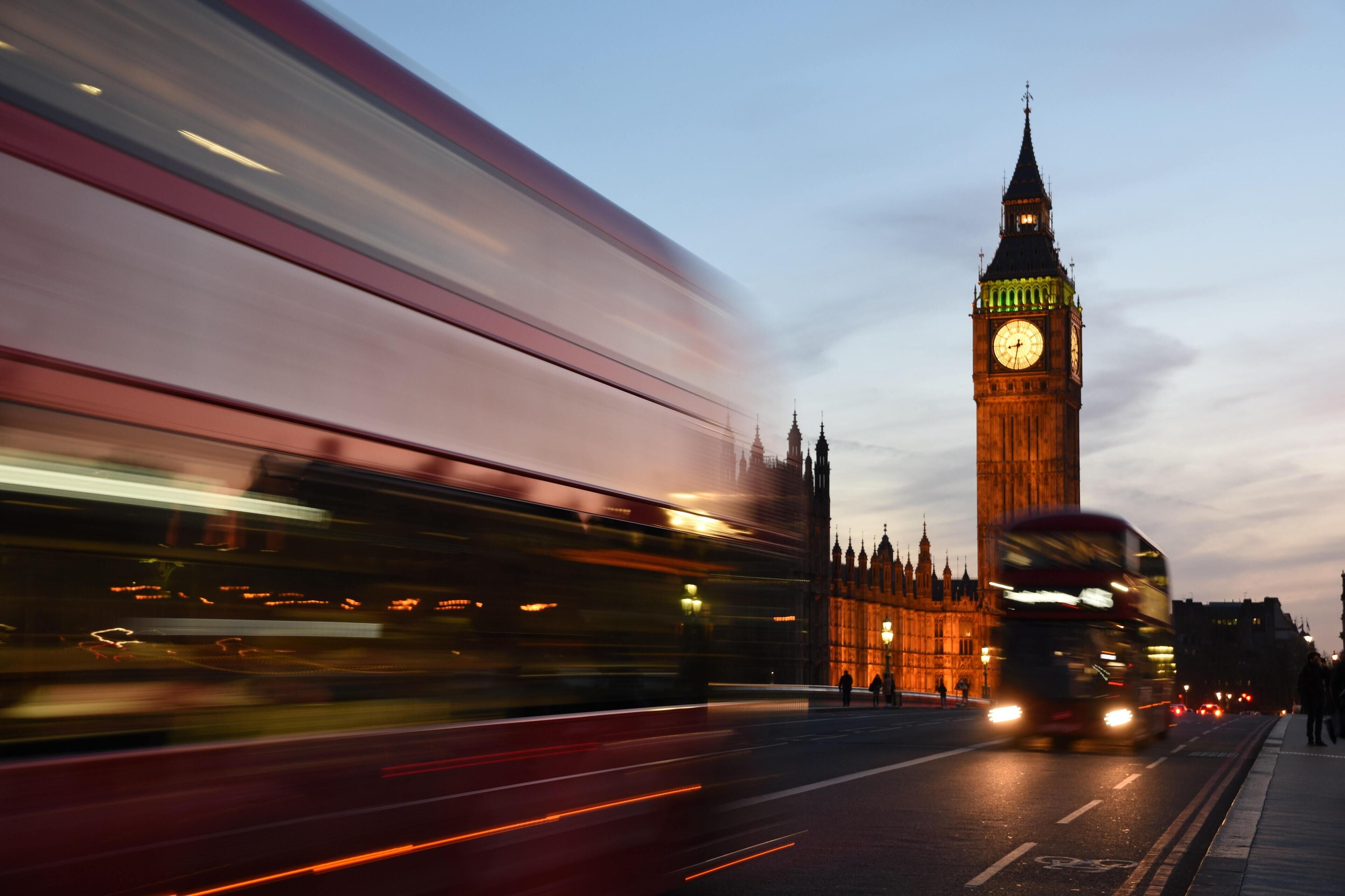 A double-decker bus in motion, with the iconic Big Ben clock tower in the background.
