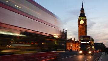 Un autobús de dos pisos en movimiento, con la icónica torre del reloj Big Ben al fondo.