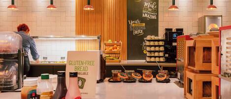 A bakery counter with gluten-free bread sign, jars of spreads, and a coffee machine.