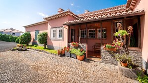 Una casa tradicional con techo de tejas, un camino de piedra y plantas en macetas.