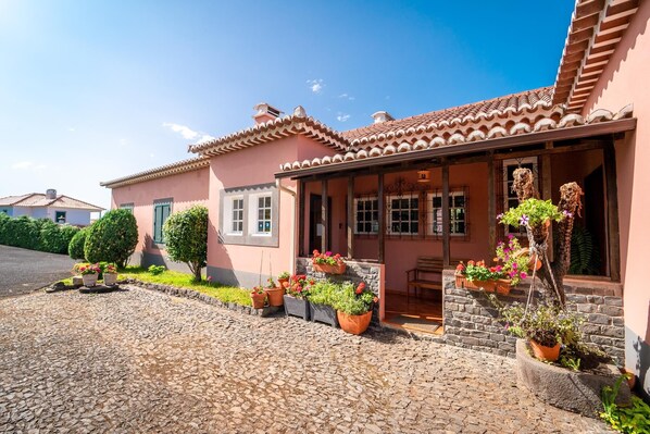 A traditional house with a tiled roof, a stone pathway, and potted plants. - Casa da Tia Clementina (Santana)