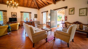 Un salón espacioso con techo de madera, televisión y chimenea.