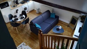 Kompakti oleskelutila, jossa on ruokailualue, sohva ja pieni keittiö.