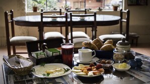 Desayuno con una mesa, sillas y diversas opciones como huevos, pastelería y bebidas.