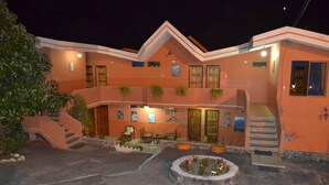 A two-story building with a central courtyard, outdoor seating, and a staircase leading to the upper level. - Hosteria Llanovientos (Baños de Agua Santa)