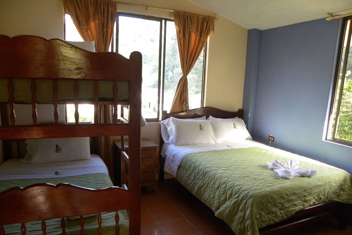 A room with two beds, a wooden headboard, a nightstand, and a window with curtains.