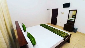 A hotel room with a bed, a dresser, a mirror, and a television on the wall. - The best home stay in Negombo.  (Ethukala)
