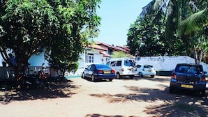 A parking area with several cars and a white van, surrounded by trees and buildings. - The best home stay in Negombo.  (Ethukala)