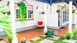 A covered outdoor area with hanging plants, a swing, and a decorative white chair. - The best home stay in Negombo.  (Ethukala)