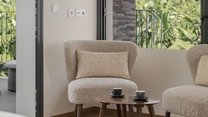 Une pièce chaleureuse avec un fauteuil moelleux, une petite table ronde avec deux tasses et une grande fenêtre donnant sur un paysage verdoyant.