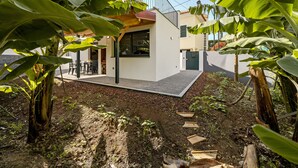 Une maison moderne dotée d’un patio, entourée de bananiers.
