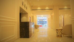 A hotel lobby with a reception desk, seating area, and a view of the street through the glass doors. - New MerryLand Hotel (Amman)