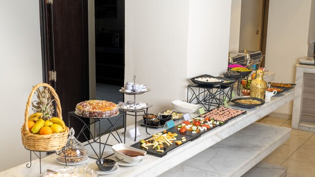 A buffet setup with various food items and a fruit basket. - New MerryLand Hotel (Amman)