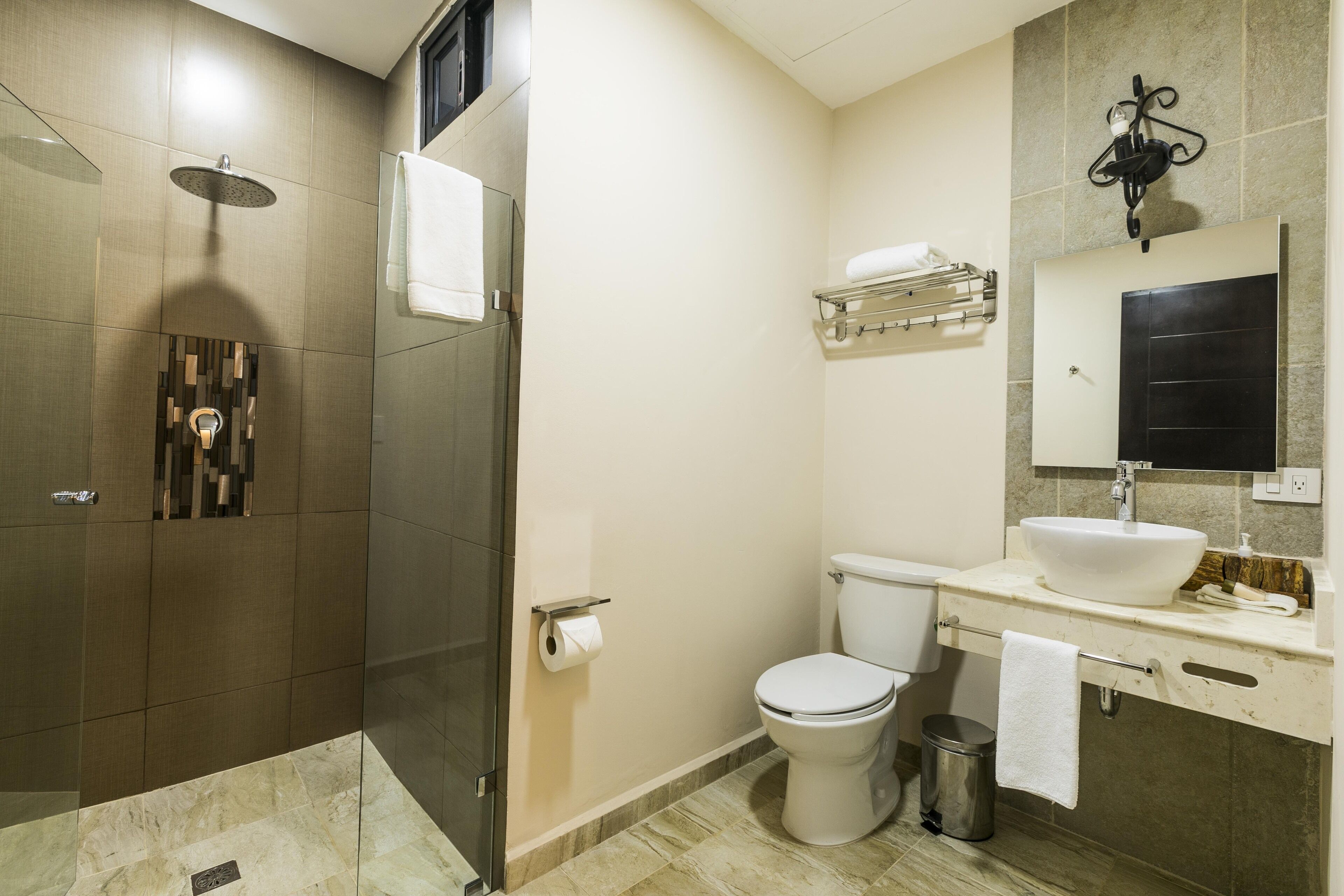 A modern bathroom with a glass-enclosed shower, a white toilet, a sink with a mirror above, and a towel rack.