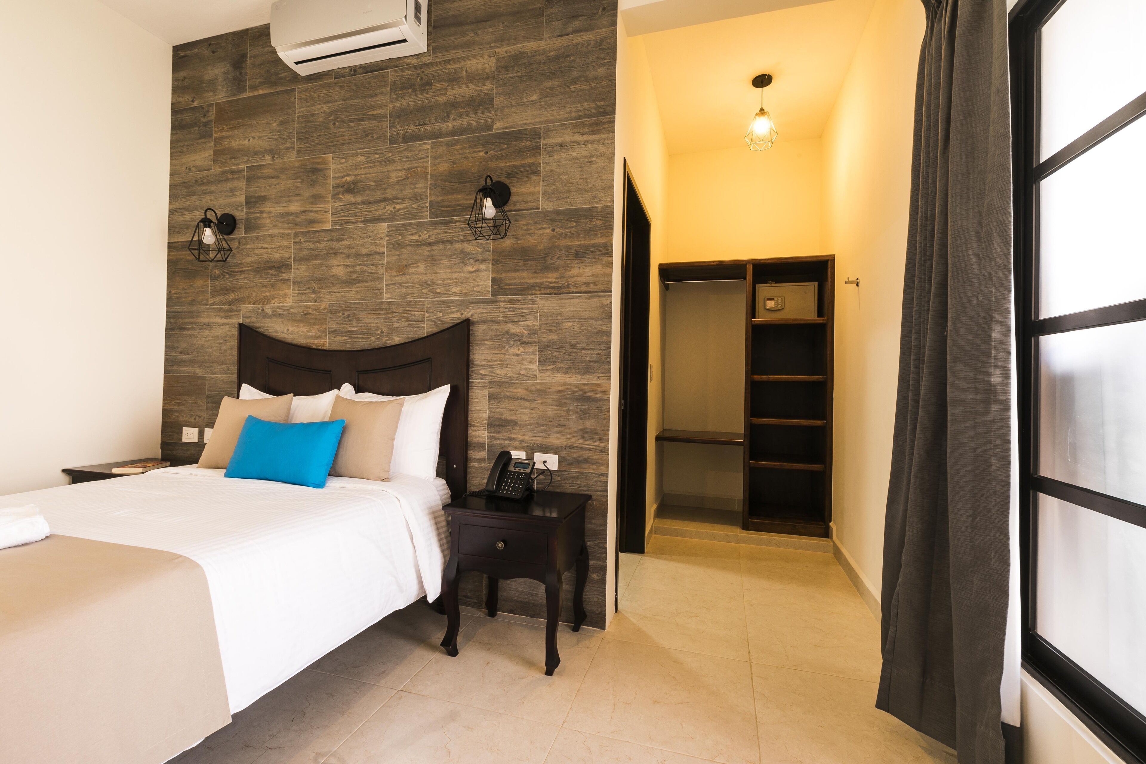 A hotel room with a bed, bedside table, phone, and a wardrobe.
