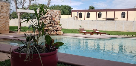 Una piscina al aire libre, sillones reclinables de piscina