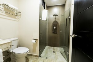 Un baño con inodoro, ducha con cerramiento de vidrio y puerta negra.
