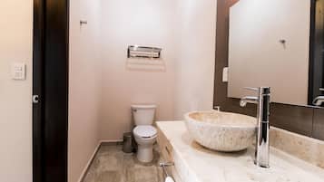 Een moderne badkamer met een groot marmeren wastafel, toilet en een spiegel boven de wastafel.