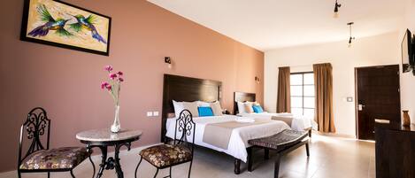 A hotel room with a bed, a small round table with chairs, a decorative vase, and a painting on the wall.