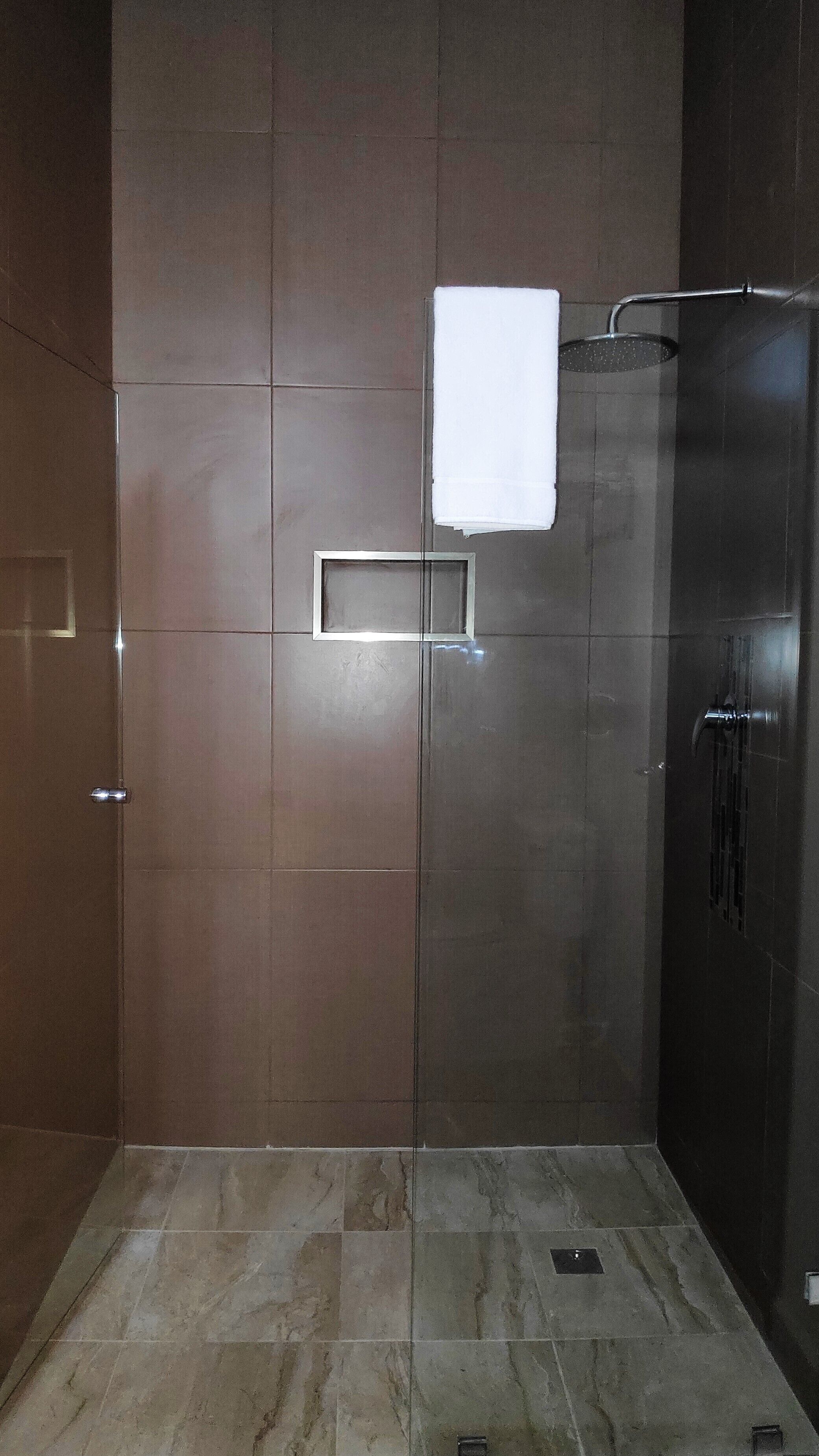 A modern bathroom with a glass shower enclosure, a towel rack, and a built-in towel dispenser.