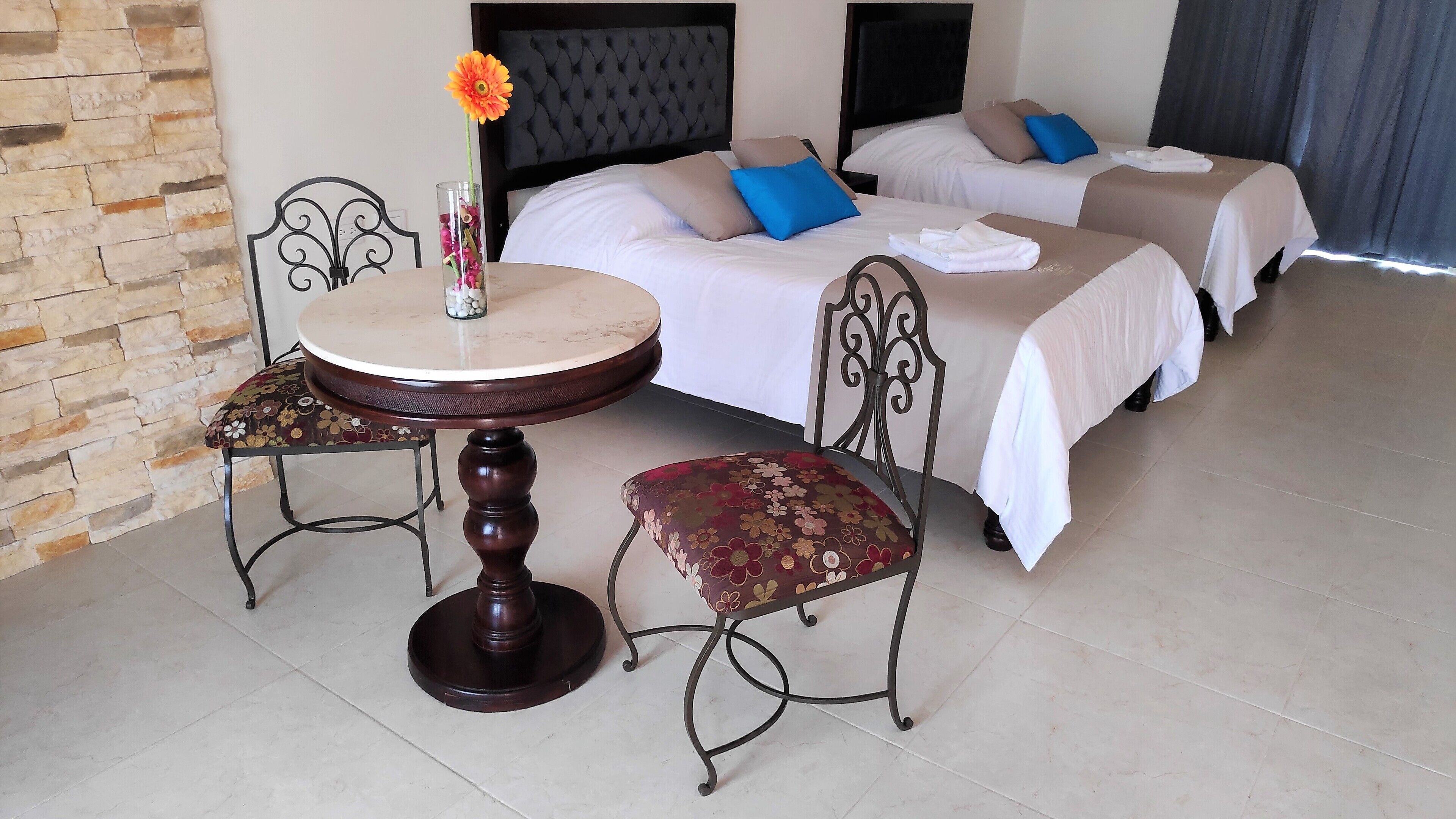 A hotel room with a bed, two bedside tables, a round table, and two chairs.